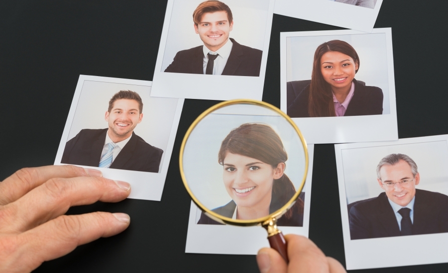 photos of business people, one image, that of a woman in spotlighted under a magnifying glass