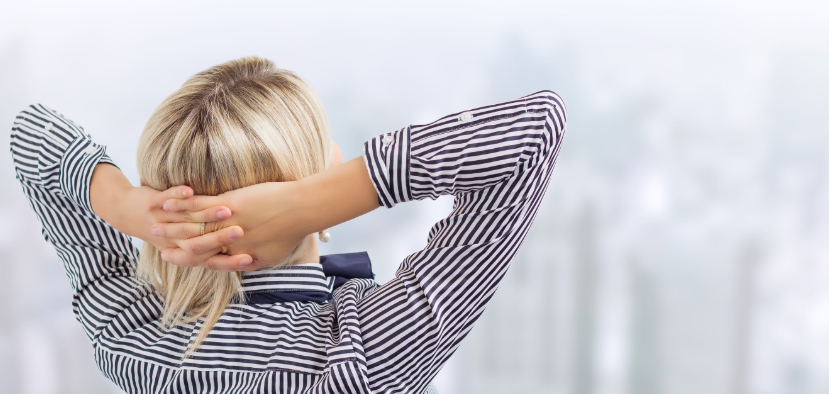 Business woman leaning back on chair surveying the cityscape muted in front of her