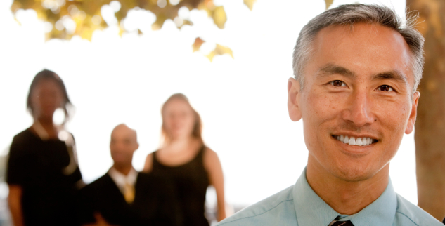 attractive asian businessman with team in background