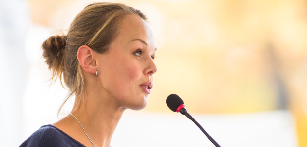 Attractive young business woman speaking over mic to group, out of shot